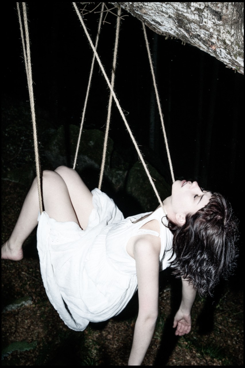 Tied — Anfisa seated in a rope swing beneath a rock overhang