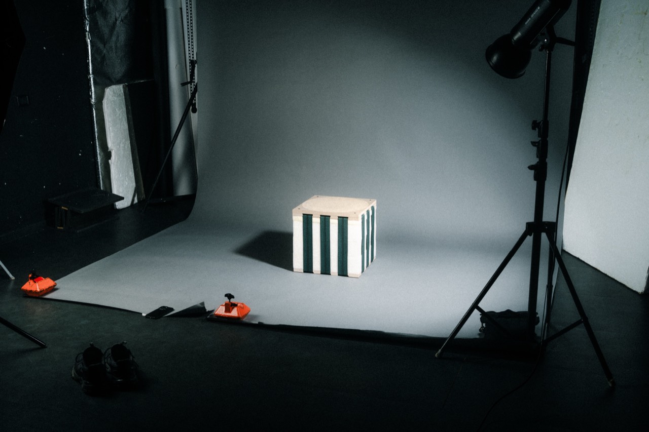Inverso stool by Tom Pradella — foam body with upholstery straps and wooden seat, studio view