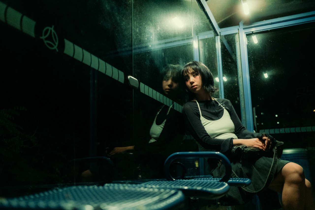 Madame Butterfly — Jenny seated in a glass bus shelter at night, Munich; photograph by Tom Pradella