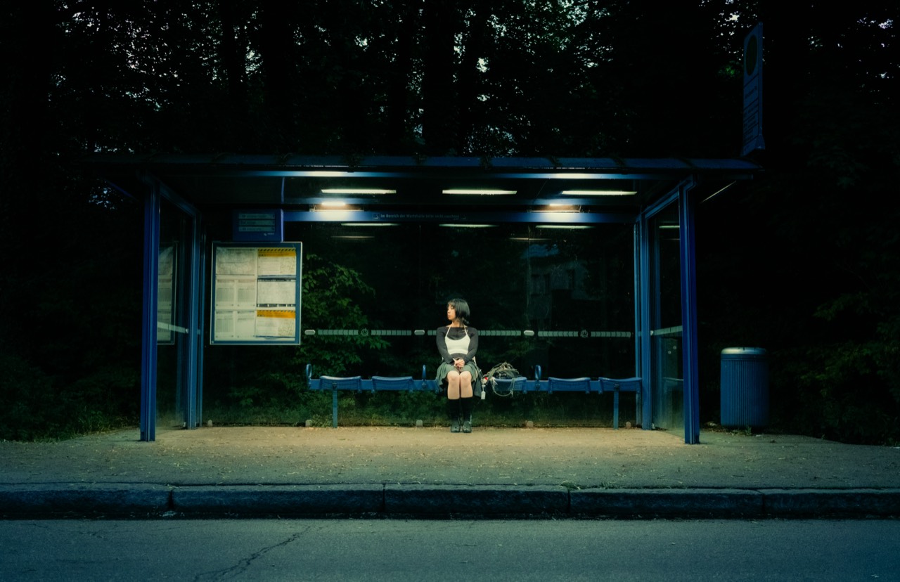 Madame Butterfly — wide view of a lit bus stop at night, Munich